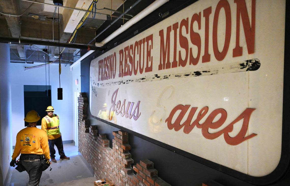 Workers continue construction inside The Fresno Mission’s new Heartbeat Hub before receiving a $500,000 grant from Bank of America Wednesday, Oct. 12, 2022 in Fresno. The Fresno Rescue Mission sign and bricks to the right are originals, salvaged for the new facility.