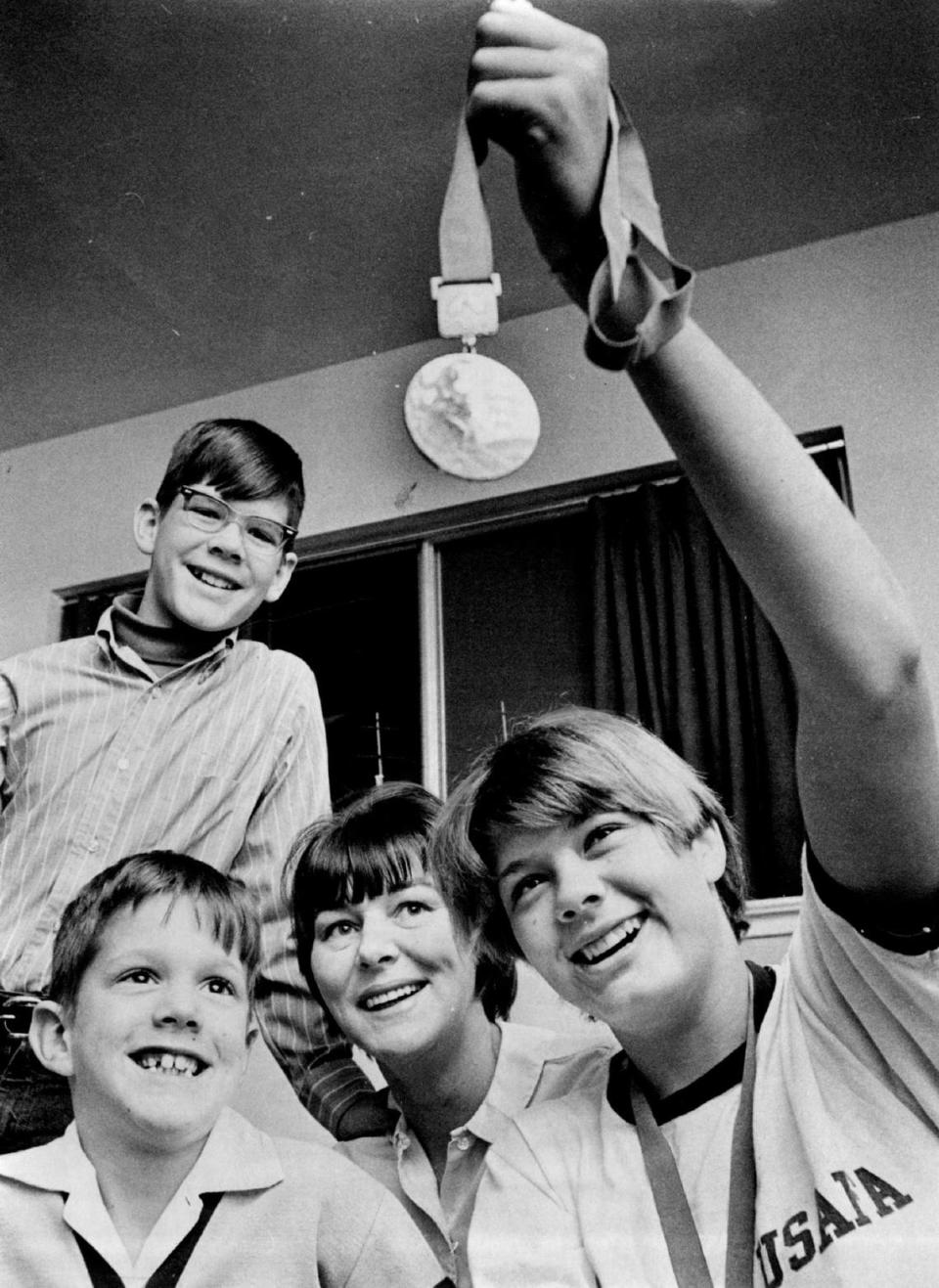 Sacramento’s Debbie Meyer, celebrating being named winner of the James E. Sullivan Memorial Award as America’s amateur athlete of 1968, holds up an Olympic gold medal and wears another. The third one she gave to her coach, Sherm Chavoor. With Debbie in her home are her mother Betty and brothers Jeff, 12, above, and Carl, 8.