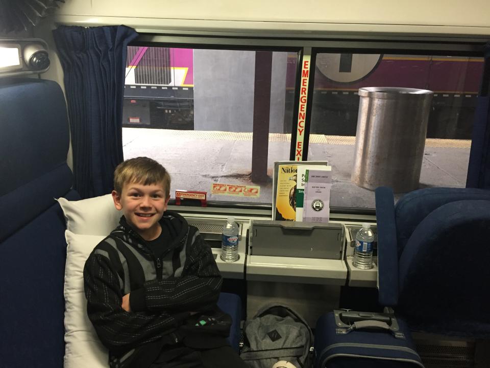 The writer's son seated on a train, smiling.