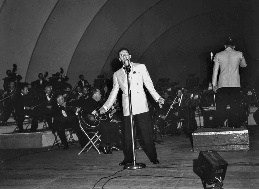 A man sings with an orchestra onstage.