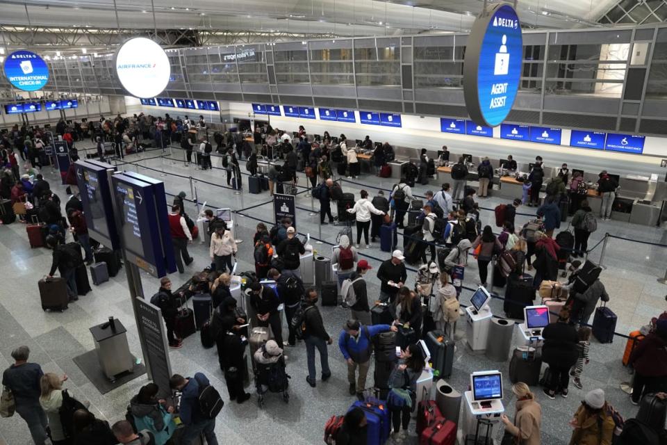 Travelers check in at kiosks and wait in line to check luggage at Minneapolis-St. Paul Airport in Minnesota last December. With kids in tow, checking bags means less juggling. (Photo by Abbie Parr / AP)