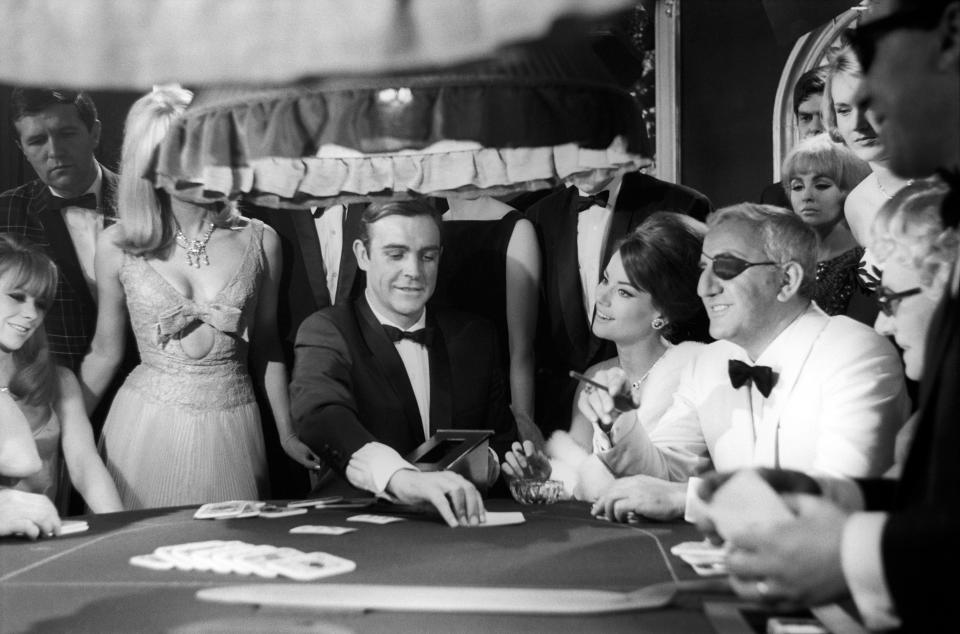 The actors Sean Connery, Claudine Auger and Adolfo Celi prepare the scene at the casino from the movie Thunderball by Terence Young, fourth episode of secret agent 007's series. Pinewood (London), march 1965. (Photo by Mario De Biasi/Mondadori via Getty Images)