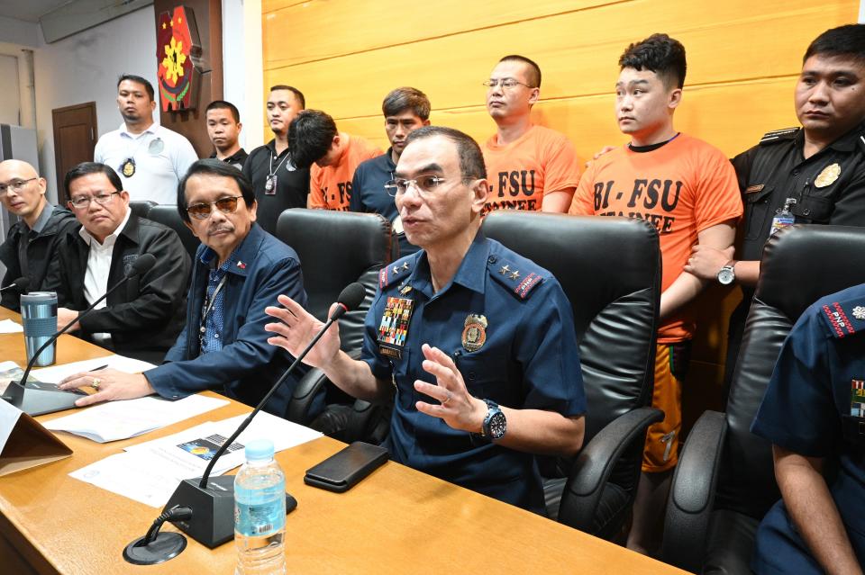 Police capital regional commander Police Major General Guillermo Eleazar (2nd R) gestures while chairman of the Presidential anti-corruption commission Dante Jimenez (3rd L) and Bureau of Immigration deputy commissioner Tobias Javier (2nd L)listen during a press conference where three (back, orange shirts) of the 277 Chinese nationals caught in the act of conducting illegal online operations, were presented to the media in Manila on September 16, 2019. - Philippine police have arrested more than 270 Chinese nationals in a raid on a gang wanted over a vast investment fraud that cost victims in China millions of dollars, authorities said September 13. (Photo by Ted ALJIBE / AFP) (Photo credit should read TED ALJIBE/AFP/Getty Images)