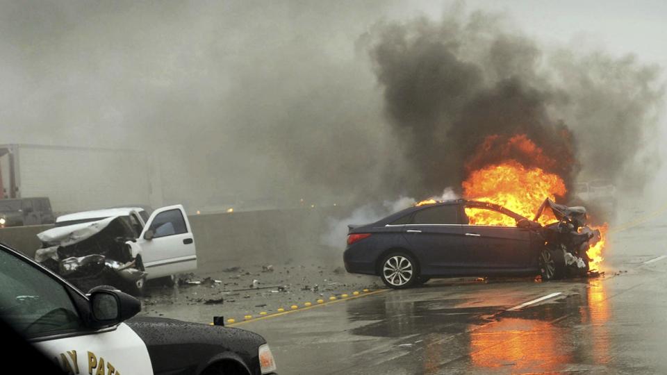 In this photo provided by John Gaps III, a car burns after a collision on rain-slick Interstate 15 just north of San Bernardino, Calif., Friday, Dec. 16, 2016. A late fall storm has drenched California, causing some mud flows, roadway flooding and traffic snarls. (John Gaps III via AP)