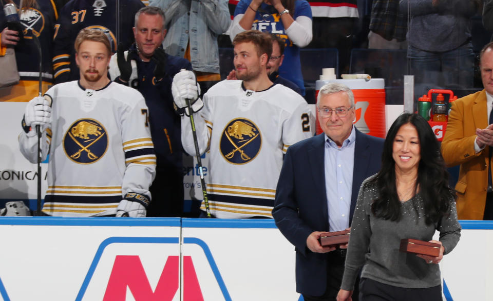 Terry y Kim Pegula posando delante de jugadores de los Buffalo Sabres.