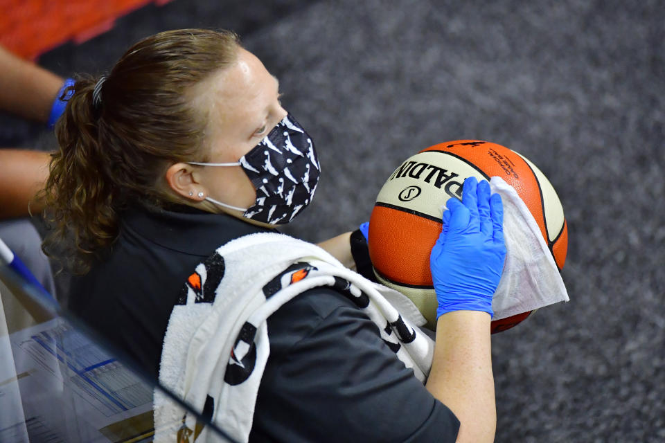 A staff member sanitizes a game ball that went out of bounds as part of the league's COVID-19 protocols. (Photo by Julio Aguilar/Getty Images)