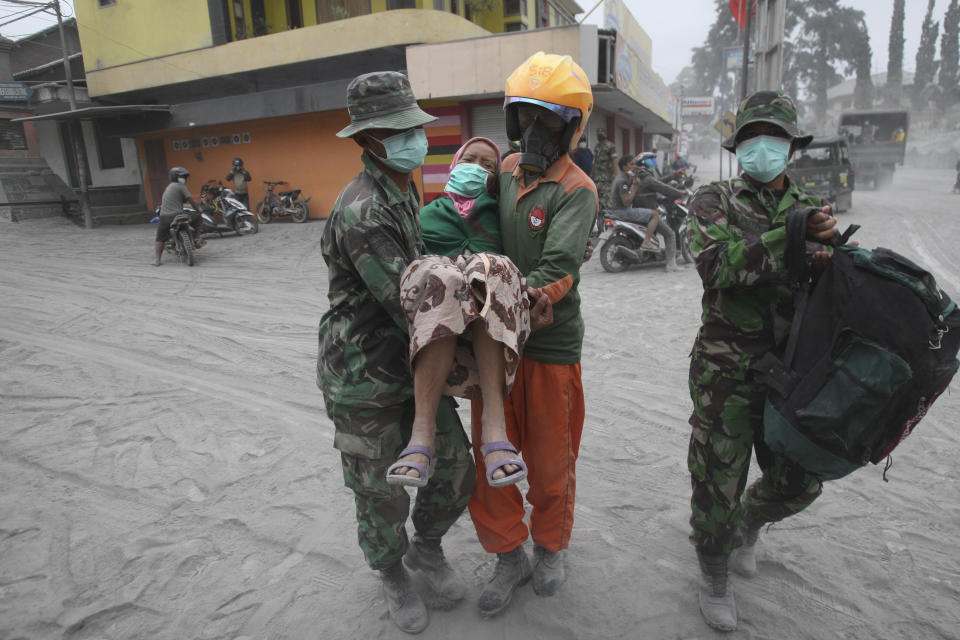 Soldiers and rescuers carry a woman to a truck for evacuation following an eruption of Mount Kelud, in Malang, East Java, Indonesia, Saturday, Feb. 15, 2014. The powerful volcanic eruption on Indonesia's most populous island blasted ash and debris 18 kilometers (12 miles) into the air Friday, forcing authorities to evacuate more than 100,000 and close seven airports. (AP Photo/Trisnadi)