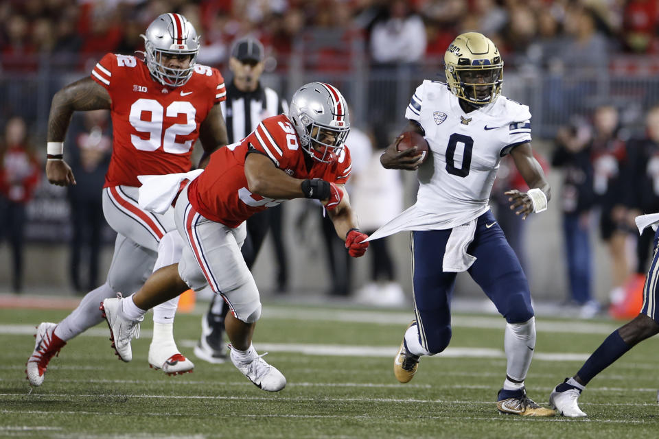 Akron quarterback DJ Irons (0) cuts upfield while pursued by Ohio State defensive lineman Haskell Garrett (92) and linebacker Cody Simon (30) during the first half of an NCAA college football game Saturday, Sept. 25, 2021, in Columbus, Ohio. (AP Photo/Jay LaPrete)