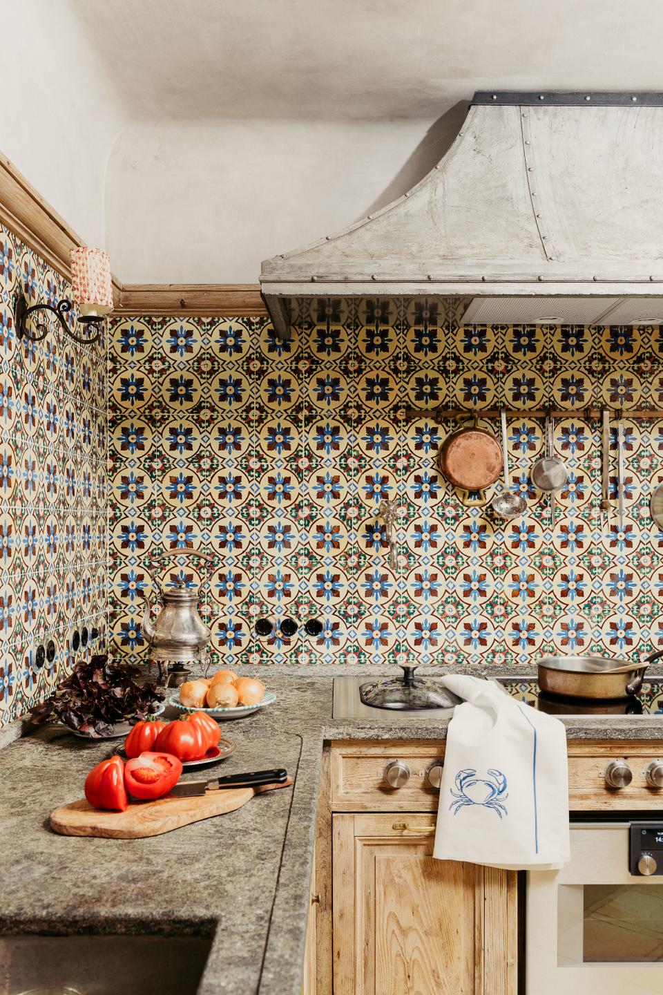 A custom iron hood by Studio Peregalli mixes with Portuguese tiles in the kitchen. Peperino marble countertops; Fir cabinetry.