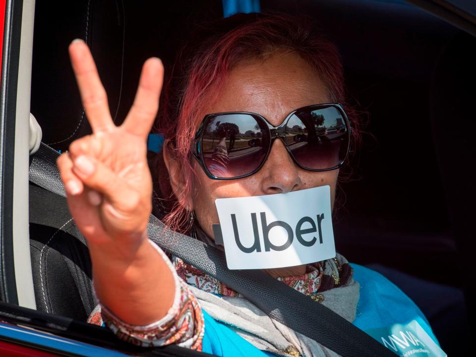 A protester gestures as Uber and Lyft drivers drive through Beverly Hills on their way to demonstrate outside the recently purchased $72 million home of Uber co-founder Garrett Camp, to protest the first day of an "IPO cash out" in Beverly Hills, California on November 6, 2019. - The drivers claim that "executives are poised to cash out their IPO billions while at the same time continuing to drive down worker pay, leaving many drivers sleeping in their cars and unable to provide for their families". (Photo by Mark RALSTON / AFP) (Photo by MARK RALSTON/AFP via Getty Images)