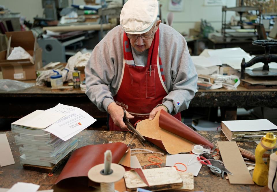 Ron Bowman, 86, cuts material to make a new cover for a book at Beck & Orr Book Binding on the Hilltop, which has been in business since 1888. Ron has been there since 1956. Their specialty is the repair and restoration of old books and they work on many Bibles but also bind theses, magazines and 