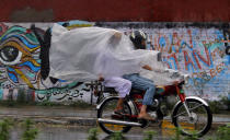 <p>Pakistanis use a plastic sheet to protect themselves from rain in Rawalpindi, Pakistan, July 27, 2016. Monsoon season in Pakistan begins in July and ends in September. (Photo: Anjum Naveed/AP)</p>