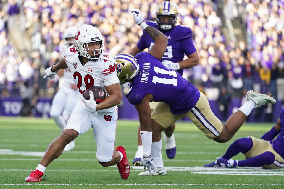 Utah running back Sione Vaki (28) avoids a tackle from Washington linebacker Alphonzo Tuputala (11) during the first half of an NCAA college football game Saturday, Nov. 11, 2023, in Seattle. (AP Photo/Lindsey Wasson)