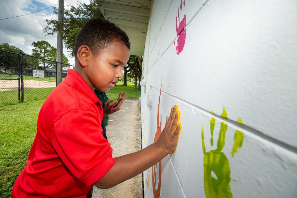 Paxton Amos, 6, places a painted handprint on a new mural at Spence Park In Mulberry. He and other youngsters added personal touches to the mural, which broadcasts the word "believe" as an inspiration for Mulberry's youngsters.