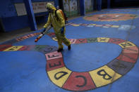 A government employee disinfects a public school as a measure against the spread of the new coronavirus, in the Taguatinga neighborhood of Brasilia, Brazil, Tuesday, July 28, 2020. The local government has began preparing for the safe reopening of schools in mid-August, as restrictions related to the COVID-19 lockdown are eased. (AP Photo/Eraldo Peres)