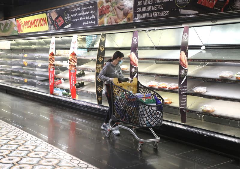 A customer pushes her trolley next to near empty shelves after people hoarded food as authorities are discussing the latest measures to implement to curb the spread of the coronavirus disease (COVID-19), in Beirut