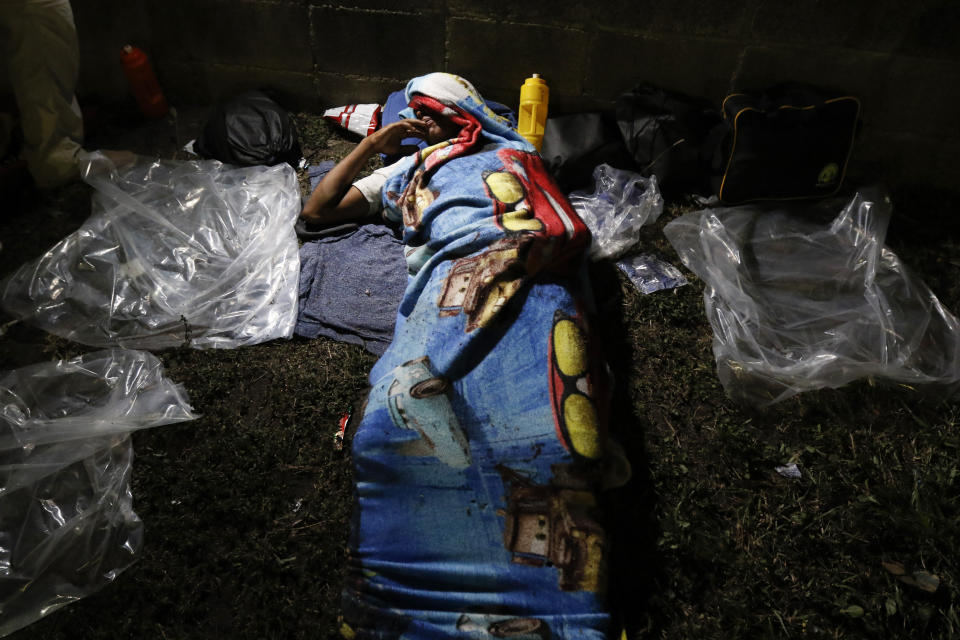 A person lies on the ground before dawn, waiting for his group to be ready to leave on foot from San Pedro Sula, Honduras, Tuesday, March 30, 2021. The group of migrants aims to reach the U.S. (AP Photo/Delmer Martinez)