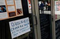A "Waiter needed" sign hangs from restaurant window in central Madrid