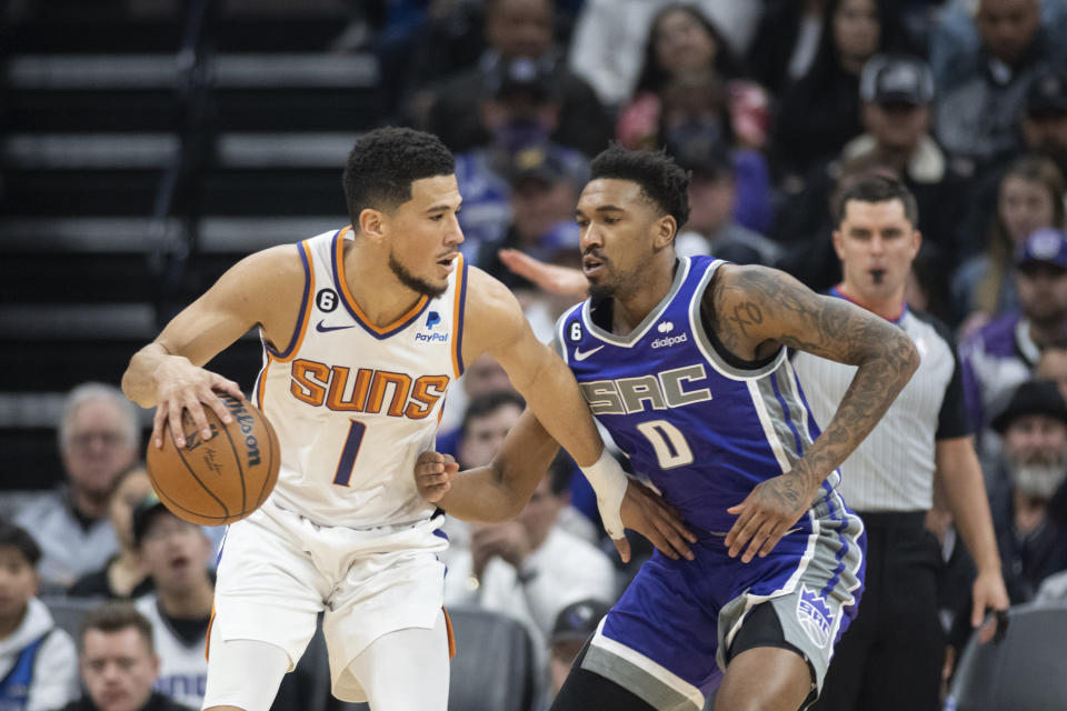 Sacramento Kings guard Malik Monk (0) defends against Phoenix Suns guard Devin Booker (1) in the first quarter in an NBA basketball game in Sacramento, Calif., Friday, March 24, 2023. (AP Photo/José Luis Villegas)