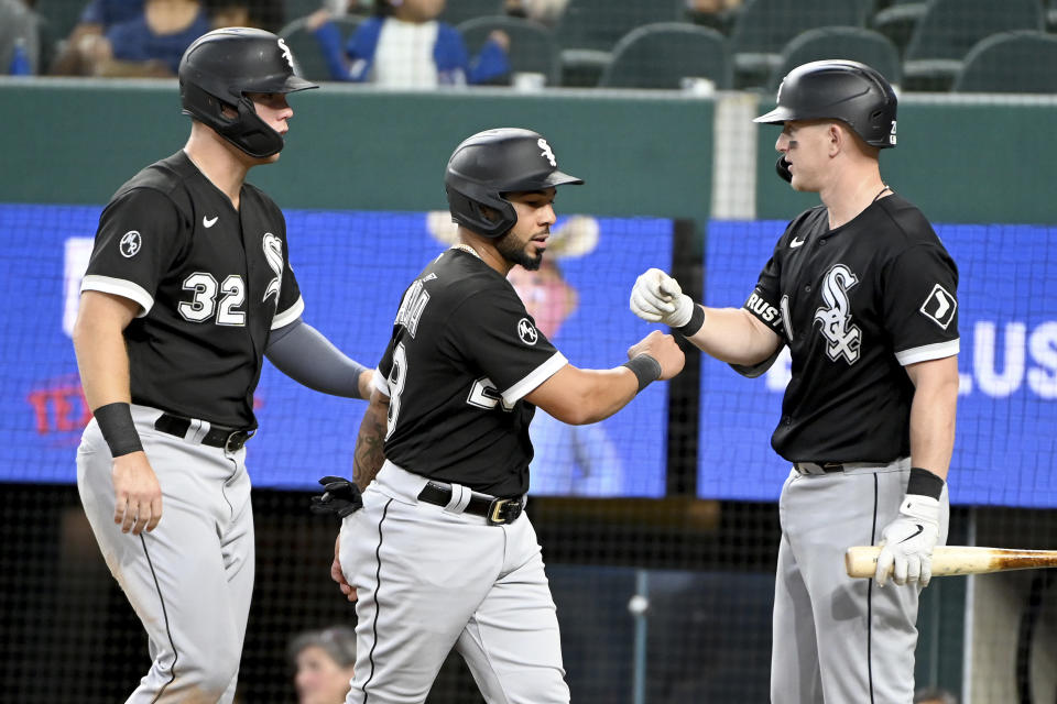 Chicago White Sox' Gavin Sheets (32) and Leury Garcia, center, are congratulated by teammate Zack Collins after scoring runs in the fourth inning during a baseball game against the Texas Rangers in Arlington Texas, Sunday, Sept. 19, 2021. (AP Photo/Matt Strasen)