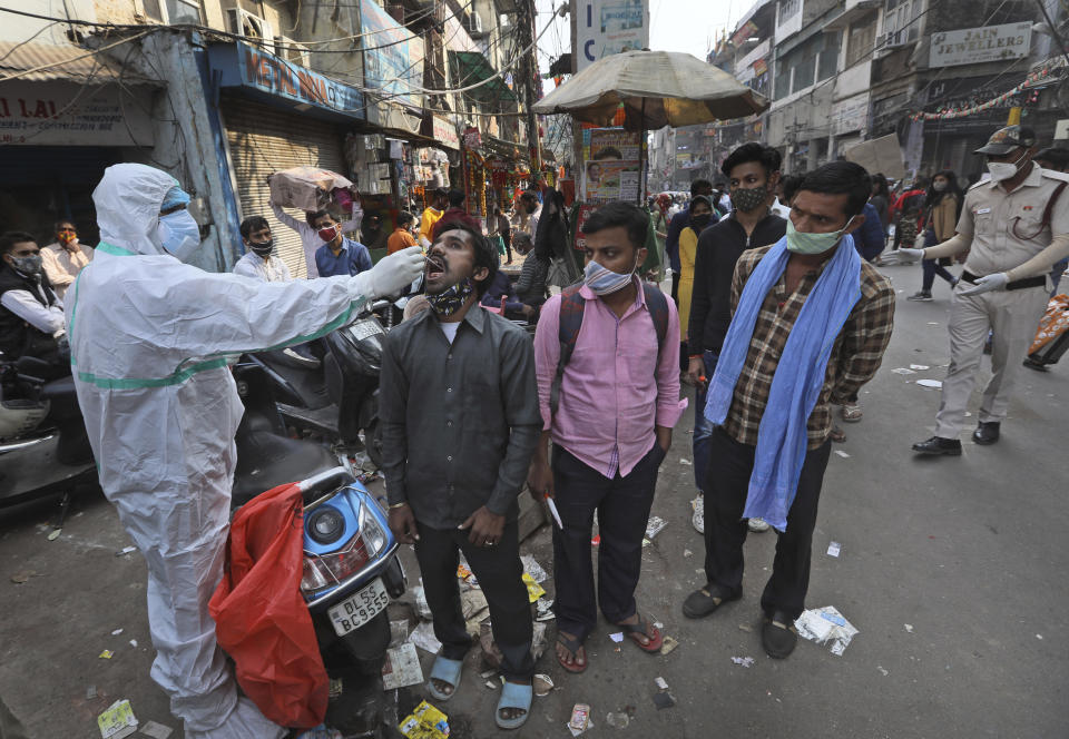 A health worker takes a sample to test for COVID-19 test at a market place in New Delhi, India, Thursday, Nov. 19, 2020. India's confirmed coronavirus caseload is expected to surpass 9 million on Friday as authorities in New Delhi battle to slow down the surge of infections in the city by increasing testing. The country's overall tally of confirmed cases is currently the second largest in the world behind the United States. (AP Photo/Manish Swarup)