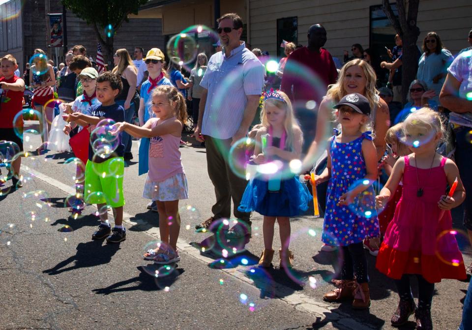 Spectators reach out to catch soap bubbles during the 2022 Creswell 4th of July celebration.