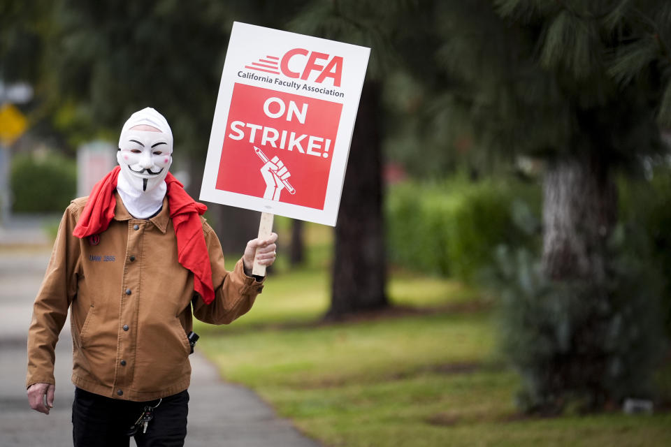 A demonstrator wears a mask outside the Cal State Northridge campus Sunday, Jan. 21, 2024, in Northridge, Calif. More than 30,000 professors, librarians, plumbers, electricians, and other workers at California State University, the largest public university system in the U.S., have started a weeklong strike on Monday to demand higher wages. (AP Photo/Marcio Jose Sanchez)