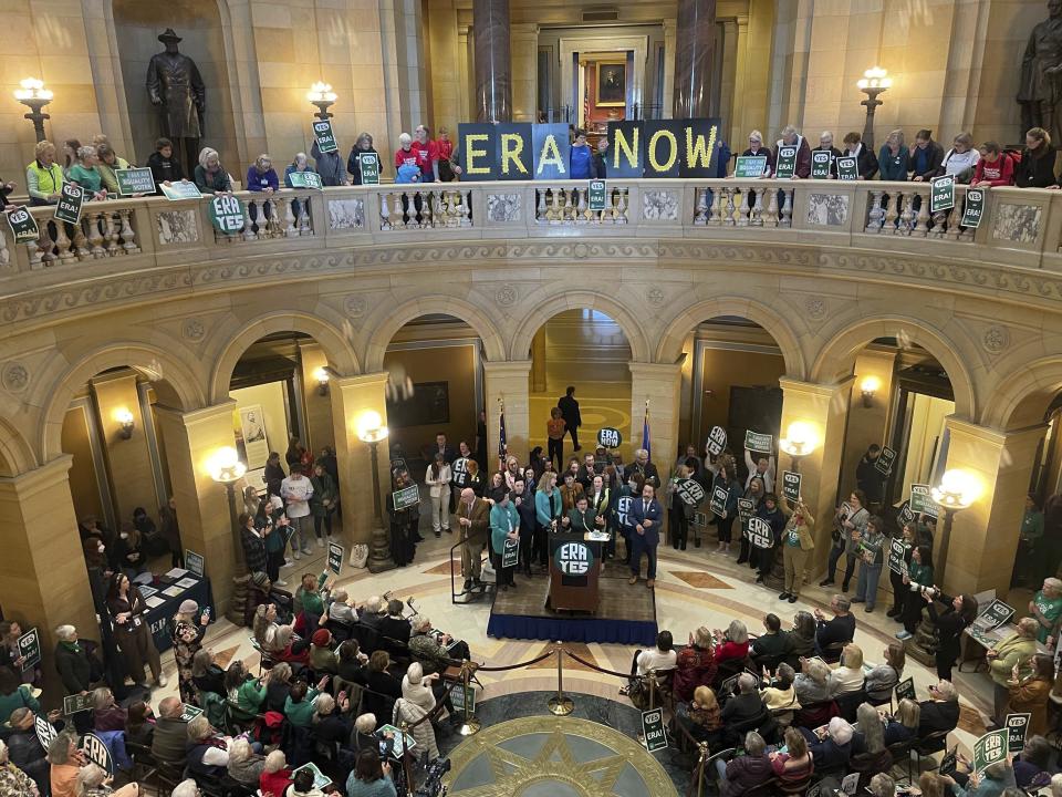 Dozens of supporters of the proposed Minnesota Equal Rights Amendment hold signs that spell out "ERA NOW" and "ERA YES" at the Minnesota Capitol building in St. Paul, Minn., Feb. 12, 2024, while Democratic lawmakers speak in support of the proposal at a podium. The proposal would be among the most expansive protections of abortion rights and LGBTQ rights in the nation if it is approved by lawmakers this session and then by Minnesota voters on the 2026 ballot. (AP Photo/Trisha Ahmed)
