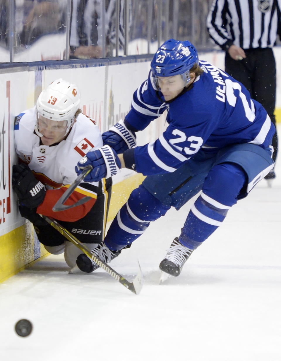 Toronto Maple Leafs defenseman Travis Dermott (23) checks Calgary Flames left wing Matthew Tkachuk (19) during the third period of an NHL hockey game Thursday, Jan. 16, 2020, in Toronto. (Nathan Denette/The Canadian Press via AP)