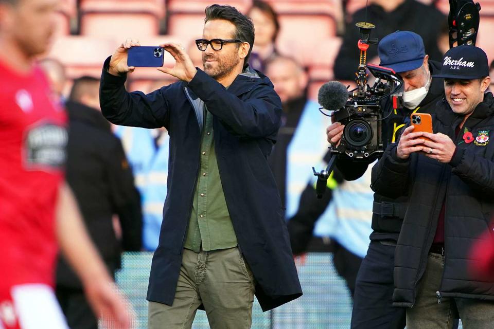 Ryan Reynolds and Rob McElhenney take photos before the Vanarama National League match at the Racecourse Ground, Wrexham. Picture date: Saturday October 30, 2021.