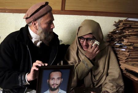 Muhammad Azeem (L) and Sajida Parveen, the parents of Ehsan Azeem, who was sentenced to death by a military court, react while holding their son's picture during an interview with Reuters in Rawalpindi January 23, 2015. REUTERS/Faisal Mahmood