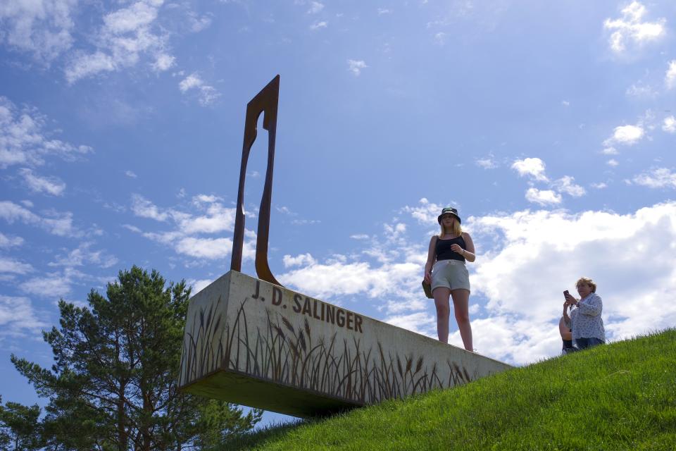 People look and photograph the new statue of American writer Jerome David Salinger in Paminklas, Lithuania, Friday, June 19, 2020. J.D. Salinger, the American writer best known for his 1951 novel "The Catcher in the Rye," has been honored with a statue in a rye field, near the Lithuanian village where his ancestors lived. (AP Photo/Vladas Sciavinskas)