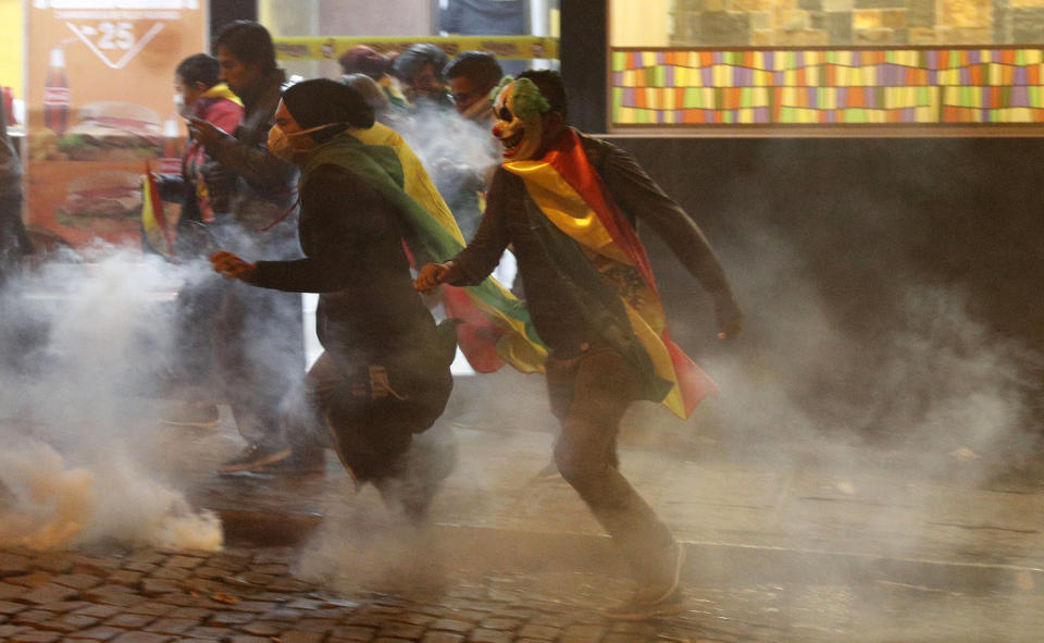 Protesters run amid tear gas fired by police during a demonstration against the reelection of President Evo Morales outside the top electoral court during the wait for final results from last weekend's presidential election in La Paz, Bolivia, Thursday, Oct. 24, 2019. Morales declared himself the outright winner Thursday of an election in which he was seeking a fourth term as president, enraging his opponents who alleged vote fraud and called for further protests to demand a second round of voting. (AP Photo/Juan Karita)
