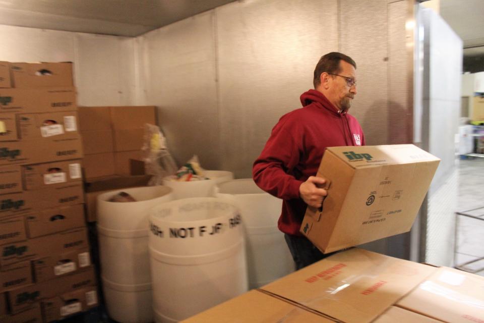 Community Food Bank employee Kris Harding hoists a box of frozen meat.