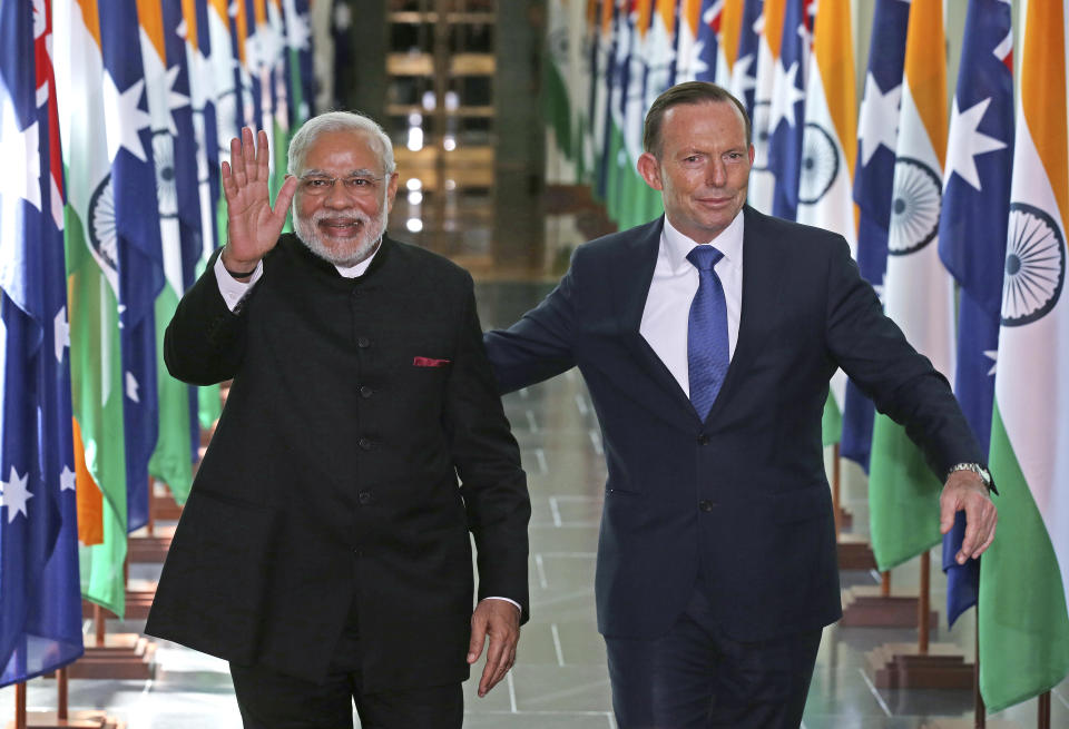 FILE - In this Nov. 18, 2014, file photo, India's Prime Minister Narendra Modi, left, waves as he is escorted by Australian Prime Minister Tony Abbott as they leave the House of Representatives at Parliament House in Canberra, Australia. An India-Australia free trade agreement would signal the "democratic world's tilt away from China," trade envoy and former Australian Prime Minister Tony Abbott has written on Monday, Aug. 9, 2021. (AP Photo/Rick Rycroft, Pool, File)