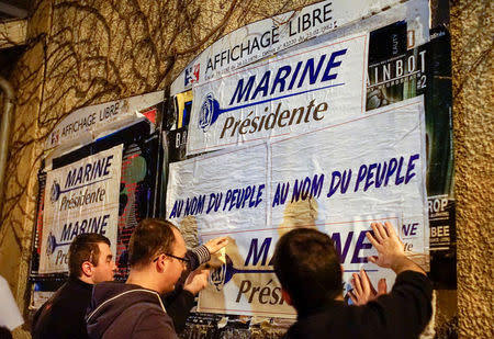 Members of the National Front youths put up posters of Marine Le Pen, French National Front (FN) political party leader and candidate for the French 2017 presidential election, ahead of a 2-day FN political rally to launch the presidential campaign in Lyon, France, February 2, 2017. REUTERS/Robert Pratta