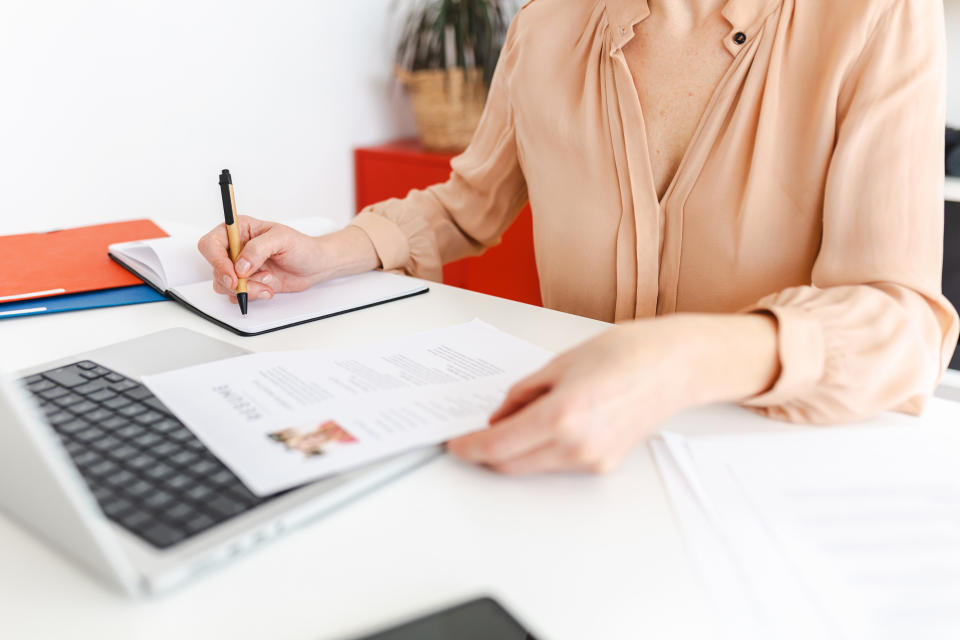 Close up view of female HR recruiter taking notes while reading job applicant resume in the office. Recruitment and hiring concept.