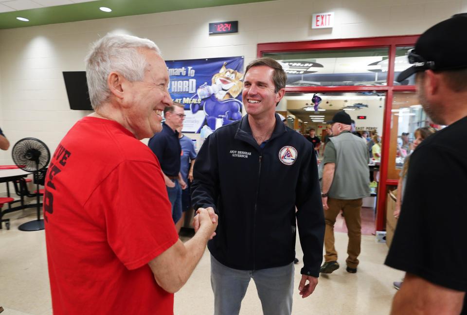 Governor Andy Beshear, center, greeted volunteer Kevin Whitman at the donation center inside the East Perry Elementary School in Hazard, Ky. on July 31, 2022.  Floods devastated the region which resulted in the deaths of over 20 people.