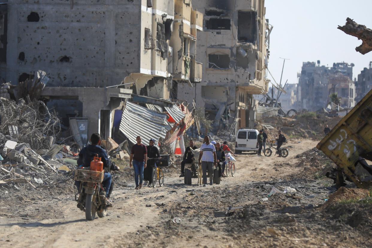 Palestinians walk through the destruction left by the Israeli air and ground offensive after they withdrew from Khan Younis, southern Gaza Strip, Sunday, April 7, 2024. (AP Photo/Ismael Abu Dayyah)