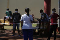 A nurse talks to people living at a school that was turned into a government-run shelter where citizens returning home are required by law to quarantine for two weeks and pass two consecutive COVID-19 tests, as a preventive measure amid the COVID-19 pandemic near Ciudad del Este, Paraguay, Wednesday, June 24, 2020. As nearby nations grapple with uncontrolled spread of the novel coronavirus, the small, poor, landlocked nation of Paraguay appears to be controlling the disease, with just a few thousand confirmed cases and a few dozen deaths. (AP Photo/Jorge Saenz)