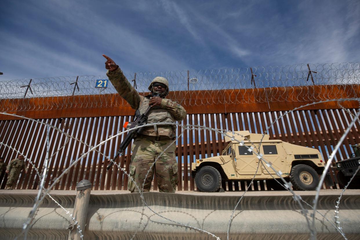 A Texas National Guard soldier, assigned to Gov. Greg Abbott's Operation Lone Star, tells migrants in the Rio Grande to use a port of entry in El Paso, Texas, in March 2023. Solders have added razor wire along several miles of the Rio Grande separating Texas from Juárez and New Mexico.