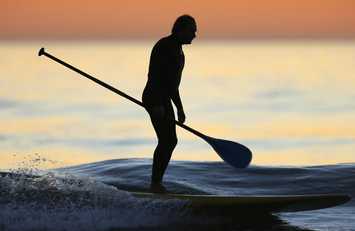 A paddle border rides in on a wave after an evening paddle off the coast of Leucadia, California. REUTERS/Mike Blake