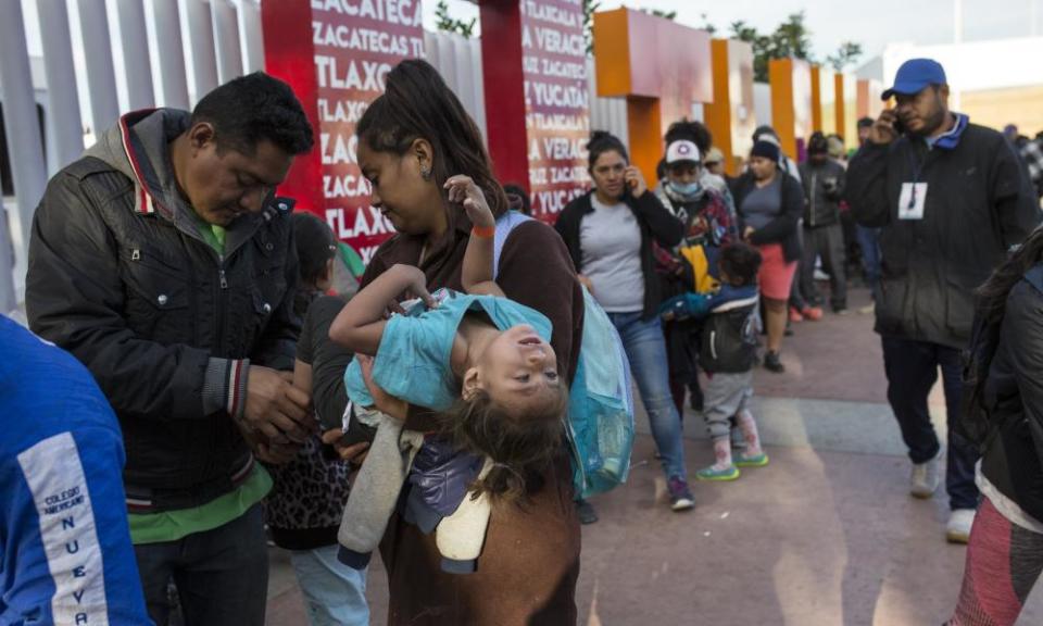Sairy Hueso carries her daughter Etzabe Ponce, as she stands next to her husband while waiting in line to receive a number as part of the process to apply for asylum in the United States, at the border in Tijuana, Mexico.