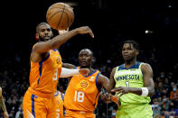 Phoenix Suns guard Chris Paul (3) reaches for a loose ball as Minnesota Timberwolves forward Anthony Edwards (1) and Phoenix Suns center Bismack Biyombo (18) look on during the first half of an NBA basketball game, Friday, Jan. 28, 2022, in Phoenix. (AP Photo/Matt York)