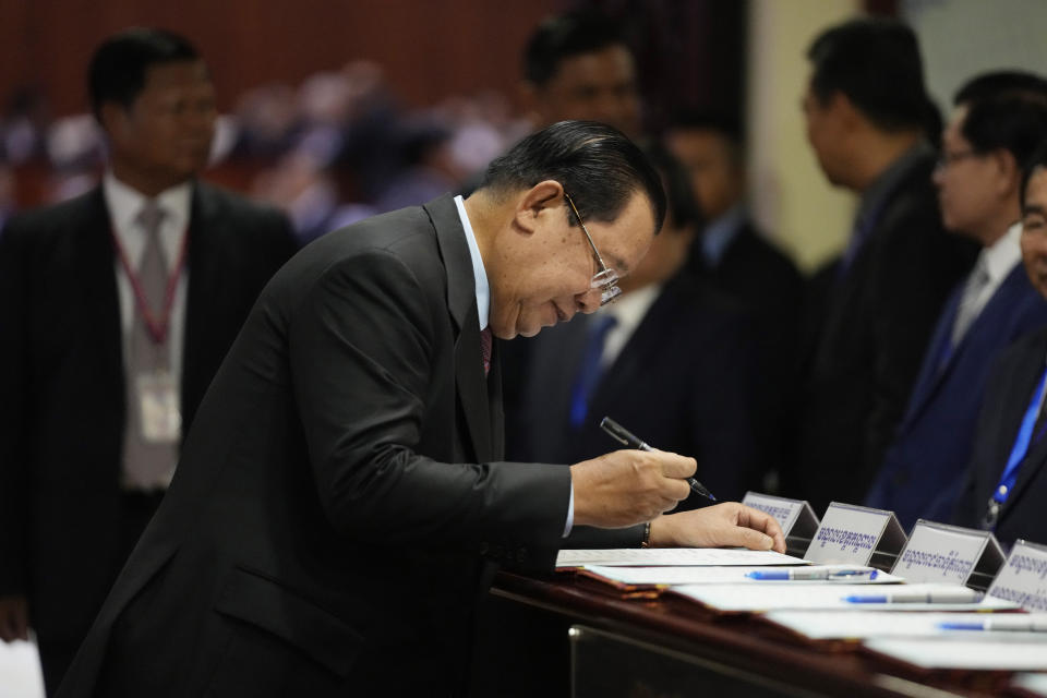 Cambodia Prime Minister Hun Sen, foreground, registers at a registration table before attending an assembly session in the National Assembly's hall in Phnom Penh, Cambodia, Tuesday, Aug. 22, 2023. (AP Photo/Heng Sinith)