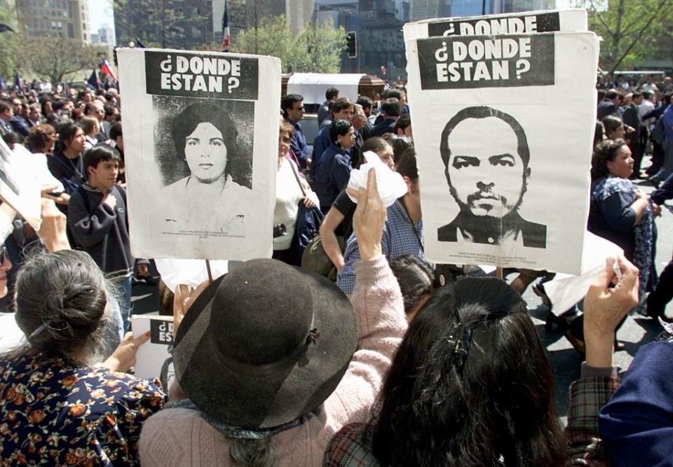 People in a crowd holding up posters asking, "¿Donde estan?"