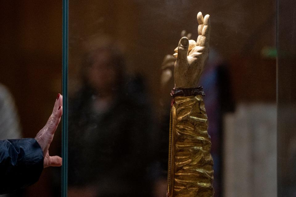 A woman places her hand near a relic of St. Jude at the Church of the Assumption in Emerson on Thursday, Dec. 7, 2023. The relic allegedly consists of a bone from the arm of St. Jude, known as the patron saint of hopeless causes and the Apostle of the Impossible, and is encased in a wooden vessel shaped like an arm within a glass case.
