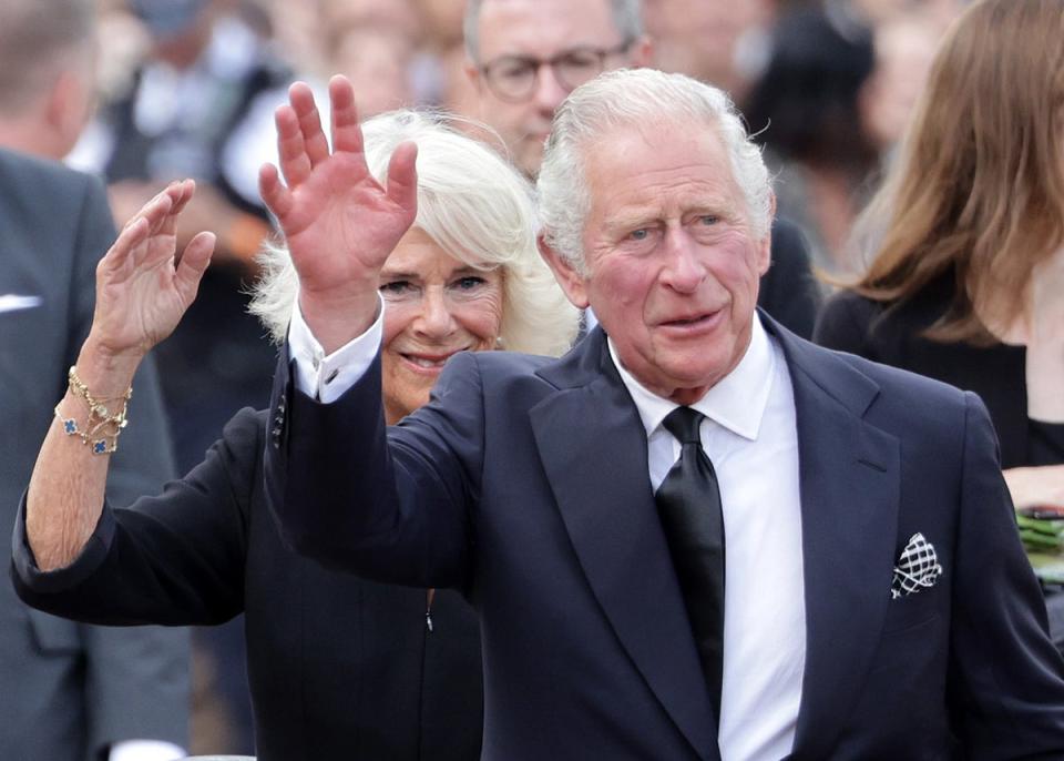 9 September 2022: King Charles III and Camilla, Queen Consort wave after viewing floral tributes to the late Queen Elizabeth II outside Buckingham Palace (Getty)