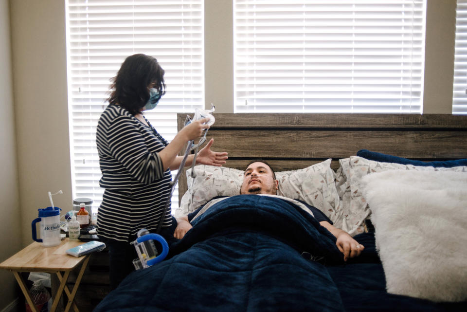 Image: Daysi Marin helps her husband fasten his CPAP machine as he returns to bed (Brandon Thibodeaux / for NBC News)