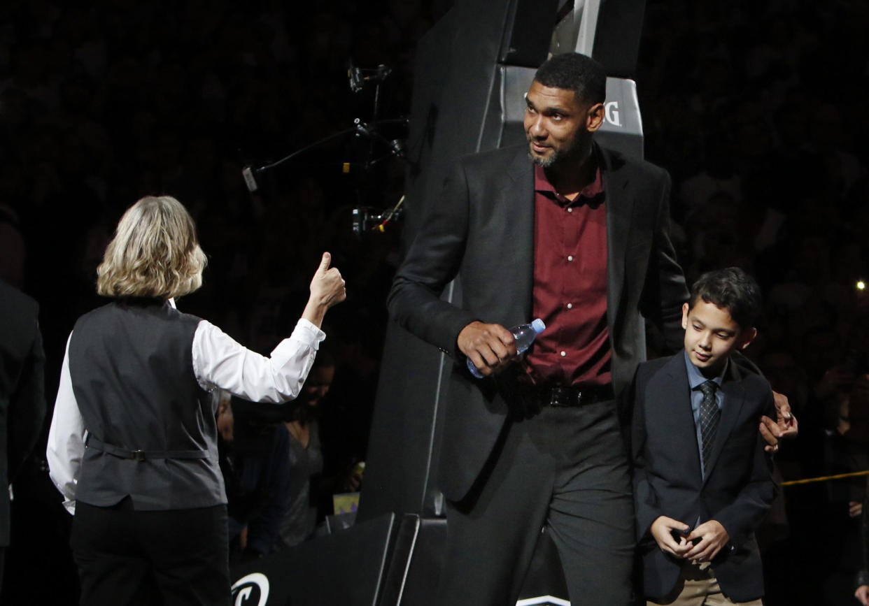 Tim Duncan walking on the court with his son during his jersey retirement ceremony.